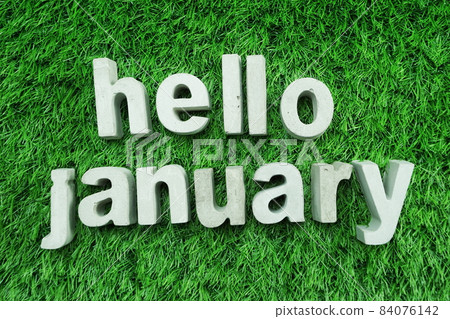 Hello January made from concrete alphabet top view on green grass 84076142