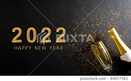 Christmas and New Year holidays background concept made from champagne and glasses with golden glitter and the text on black wooden background. Christmas and New Year holidays background concept made from champagne and glasses with golden glitter and the text on black wooden background. 84077362