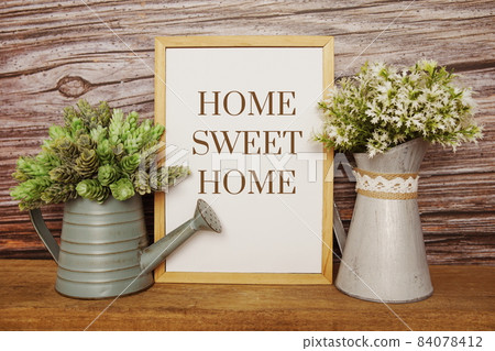 Blackboard with the text HOME SWEET HOME decorate with artificial plant in watering plant on wooden background 84078412