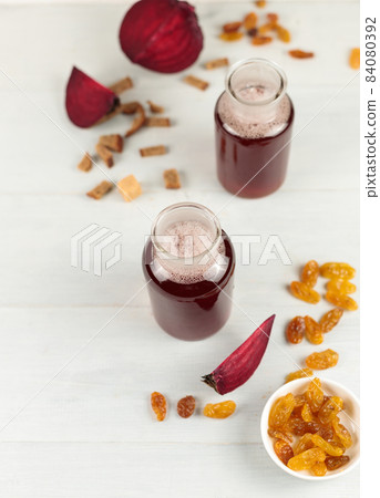 Two serving bottles with homemade beet kvass or juice. Close-up, on a light wooden table, vertical, copy space 84080392