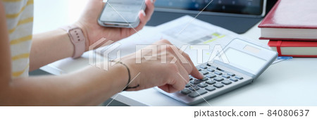 Businesswoman with smartphone calculator and laptop calculates exchange changes of stock market Businesswoman with smartphone calculator and laptop calculates exchange changes of stock market 84080637