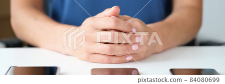 Three modern touchscreen smartphones lie on table woman with folded arms 84080699