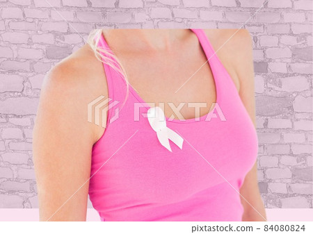 Mid section of woman wearing a pink ribbon on her sleeve against brick wall in background 84080824