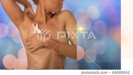 Mid section of woman wearing a pink ribbon on her chest against spots of lights on blue background Mid section of woman wearing a pink ribbon on her chest against spots of lights on blue background 84080842