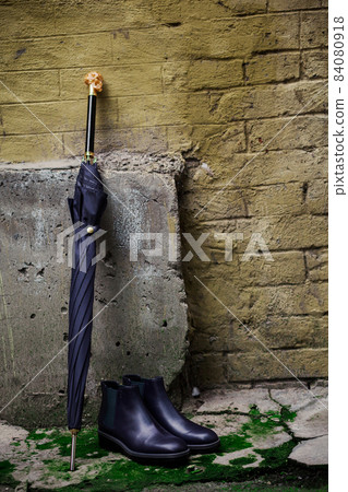 Men's shoes with an umbrella and a walking stick are on the street 84080918