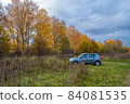 A blue passenger car on the background of grass and autumn forest. 84081535