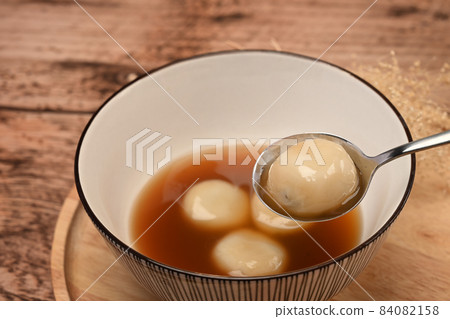 Close up rice dumpling balls with sweet ginger soup in ceramic bowl. Close up rice dumpling balls with sweet ginger soup in ceramic bowl. 84082158