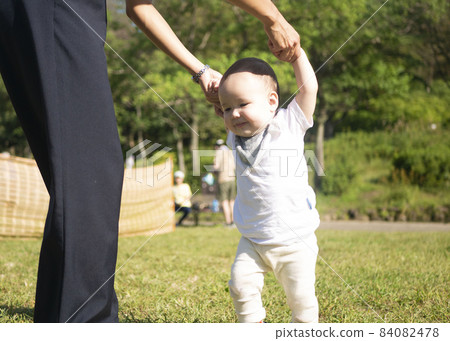 Half baby practicing walking with his mother in the park 84082478