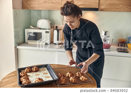 Professional confident woman is preparing custard cakes at light modern kitchen at home 84083932
