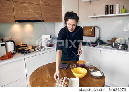 young beautiful mixed race woman is preparing marshmallow at light modern kitchen home young beautiful mixed race woman is preparing marshmallow at light modern kitchen home 84084076