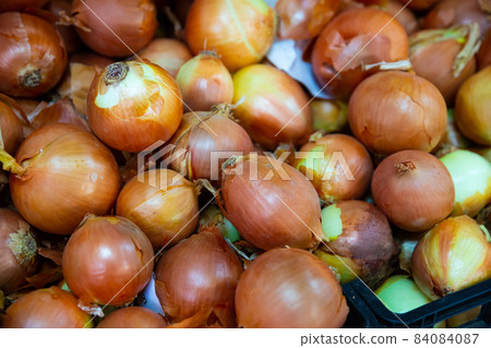 Pile of different onion varieties on market counter 84084087