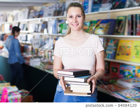 Positive woman buying books in hard cover Positive woman buying books in hard cover 84084120
