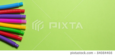 Banner with multicolored pop tubes on green paper with copy space Banner with multicolored pop tubes on green paper with copy space 84084408