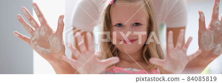 Mom and little girl showing palms of hands in flour 84085819