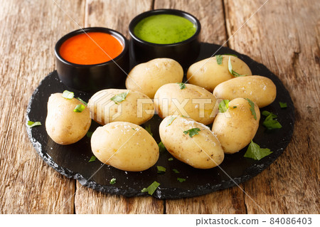 Canarian Wrinkled Potatoes Papas Arrugadas with Mojo close up in the plate. Horizontal Canarian Wrinkled Potatoes Papas Arrugadas with Mojo close up in the plate. Horizontal 84086403