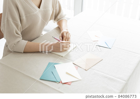 Hands of a woman writing a letter by the window Hands of a woman writing a letter by the window 84086773