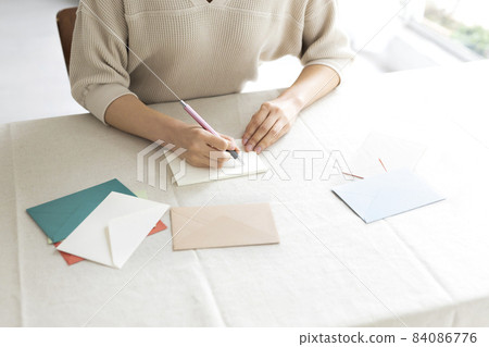 Hands of a woman writing a letter by the window 84086776