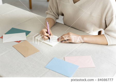Hands of a woman writing a letter by the window Hands of a woman writing a letter by the window 84086777