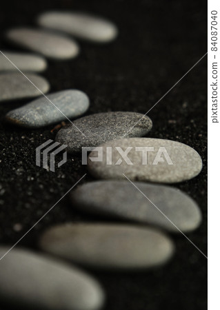 small sea pebbles are laid out on a black background small sea pebbles are laid out on a black background 84087040