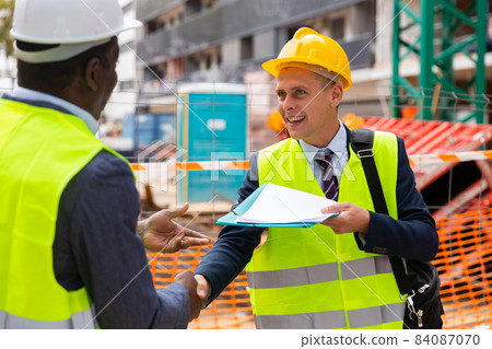 Successful architect and engineer shake hands on construction site Successful architect and engineer shake hands on construction site 84087070