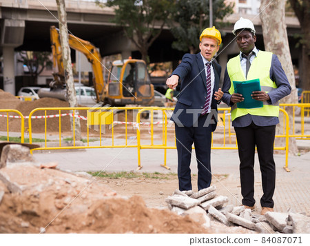 Engineers talking about road repairing outdoors Engineers talking about road repairing outdoors 84087071