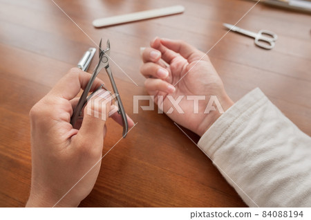 Caucasian girl makes herself a manicure at home. Close-up young woman uses nail clippers 84088194