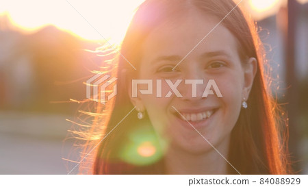 Young happy girl walks down the street smiling at sunset in the city, be satisfied with life, free woman walks in the park, walking, slow motion, student goes to study at dawn at the institute Young happy girl walks down the street smiling at sunset in the city, be satisfied with life, free woman walks in the park, walking, slow motion, student goes to study at dawn at the institute 84088929