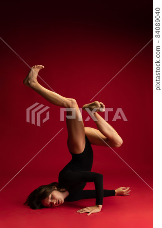 Young beautiful contemp female dancer, ballerina in art performance isolated on dark red background. Art, beauty, inspiration concept. Young beautiful contemp female dancer, ballerina in art performance isolated on dark red background. Art, beauty, inspiration concept. 84089040
