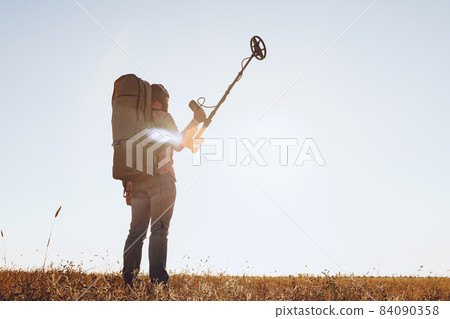 Man with metal detector equipment searching for metal goods in the field Man with metal detector equipment searching for metal goods in the field 84090358