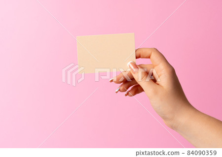 Woman hand showing blank business card on pink background. 84090359