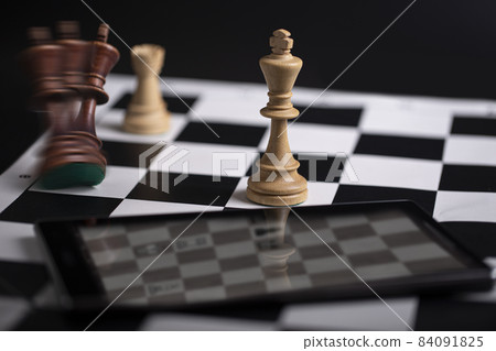 Chess pieces on a chessboard and smartphone. The concept of playing and winning a chess tournament Chess pieces on a chessboard and smartphone. The concept of playing and winning a chess tournament 84091825