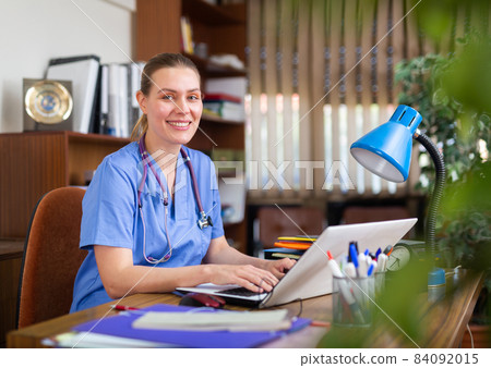 Woman doctor sitting at workplace with computer in office Woman doctor sitting at workplace with computer in office 84092015