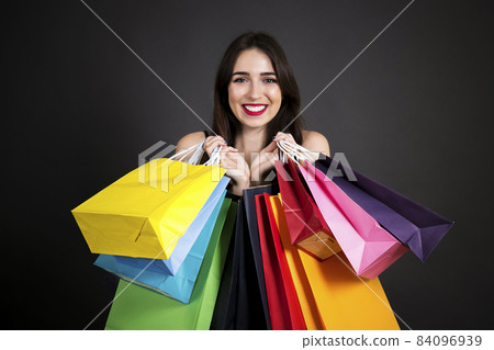 Happy brunette female with long hair in casual outfit posing over grey black gradient background. Happy brunette female with long hair in casual outfit posing over grey black gradient background. 84096939