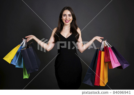 Happy brunette female with long hair in casual outfit posing over grey black gradient background. Happy brunette female with long hair in casual outfit posing over grey black gradient background. 84096941