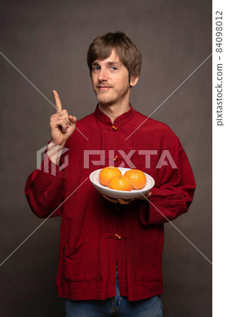 Young man with oranges on grey Young man with oranges on grey 84098012
