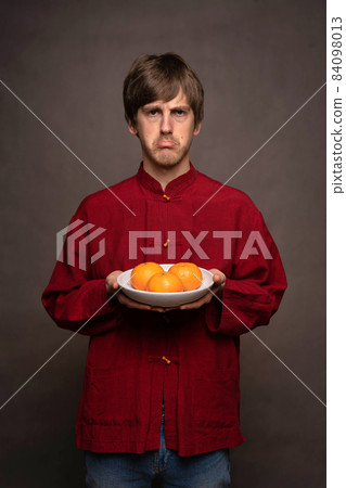 Young man with oranges on grey Young man with oranges on grey 84098013