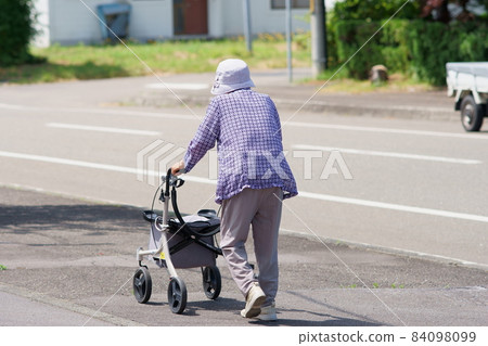 陽光明媚的日子裡，老婦人推著獨輪車散步 84098099