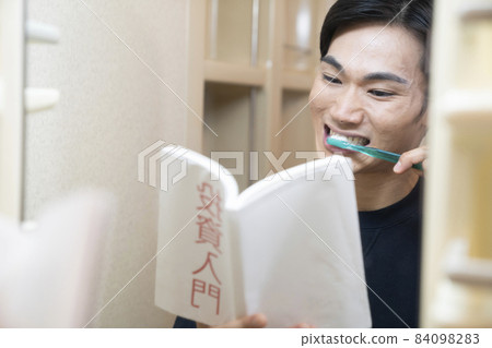 一個男人一邊在浴室刷牙一邊看書 84098283