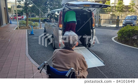 Elderly housing with care staff assisting an elderly man in a wheelchair to get on a welfare vehicle Elderly housing with care staff assisting an elderly man in a wheelchair to get on a welfare vehicle 84101649