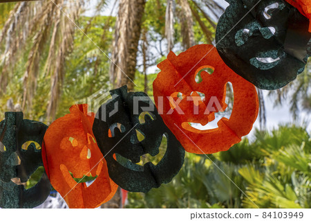 Color paper garland pumpkins for Halloween party on tropical forest background.  84103949
