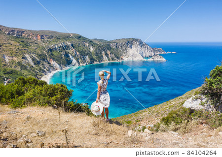 A tourist woman enjoying beautiful Petani beach on Kefalonia Ionian island, Greece, during her summer vacation holiday A tourist woman enjoying beautiful Petani beach on Kefalonia Ionian island, Greece, during her summer vacation holiday 84104264