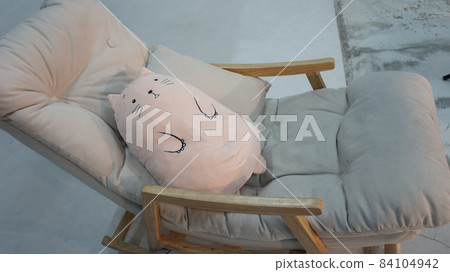 Soft toy lies on a rocking chair 84104942