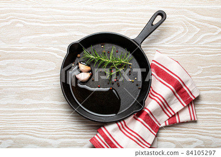 Black cast iron frying pan with rosemary, garlic, pepper, oil 84105297