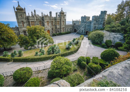 Vorontsov Palace in Alupka, Crimea. Panoramic view of castle with blue sky background. Yucca bushes and trees are in foreground 84108258