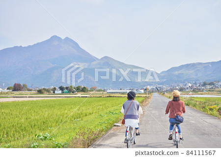 Young women and friends walking around Yufuin by bicycle 84111567