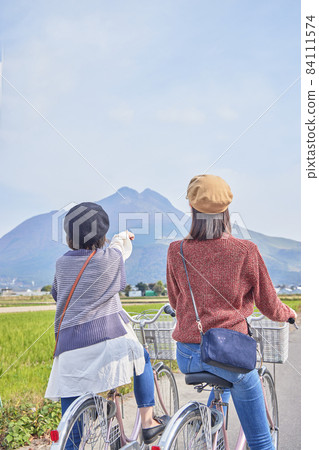 Young women and friends walking around Yufuin by bicycle 84111574