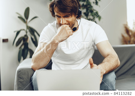 Young man businessman with headset working on laptop from home 84113282