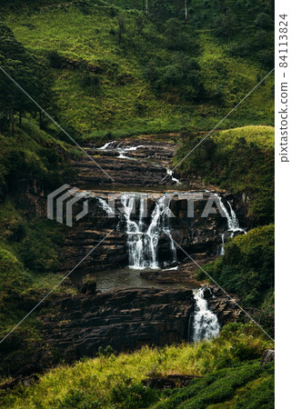 Waterfall among the green mountains. Waterfalls Of Sri Lanka. Landscapes Of Asia. Aerial photography. Tea plantation. Green hill. Mountain river. Small waterfall. Sri lanka Waterfall among the green mountains. Waterfalls Of Sri Lanka. Landscapes Of Asia. Aerial photography. Tea plantation. Green hill. Mountain river. Small waterfall. Sri lanka 84113824