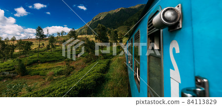 Blue train in Sri Lanka. Blue Sri Lankan Train goes through jungles, trees, wood, mountains. Travel by train in Asia, panorama. An Indian train passes through tea plantations. Travel in India Blue train in Sri Lanka. Blue Sri Lankan Train goes through jungles, trees, wood, mountains. Travel by train in Asia, panorama. An Indian train passes through tea plantations. Travel in India 84113829