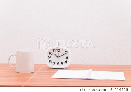 The notebook and the clock are on the table. The notebook and the clock are on the table. 84114506
